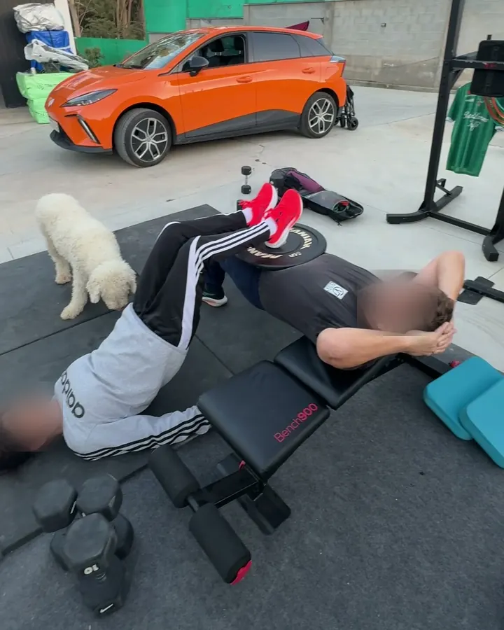 Cliente entrenando en el garaje de su casa con banco y mancuernas