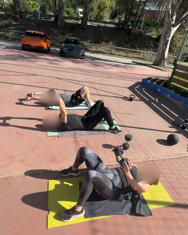 Grupo de tres personas entrenando al aire libre con mancuernas en Málaga