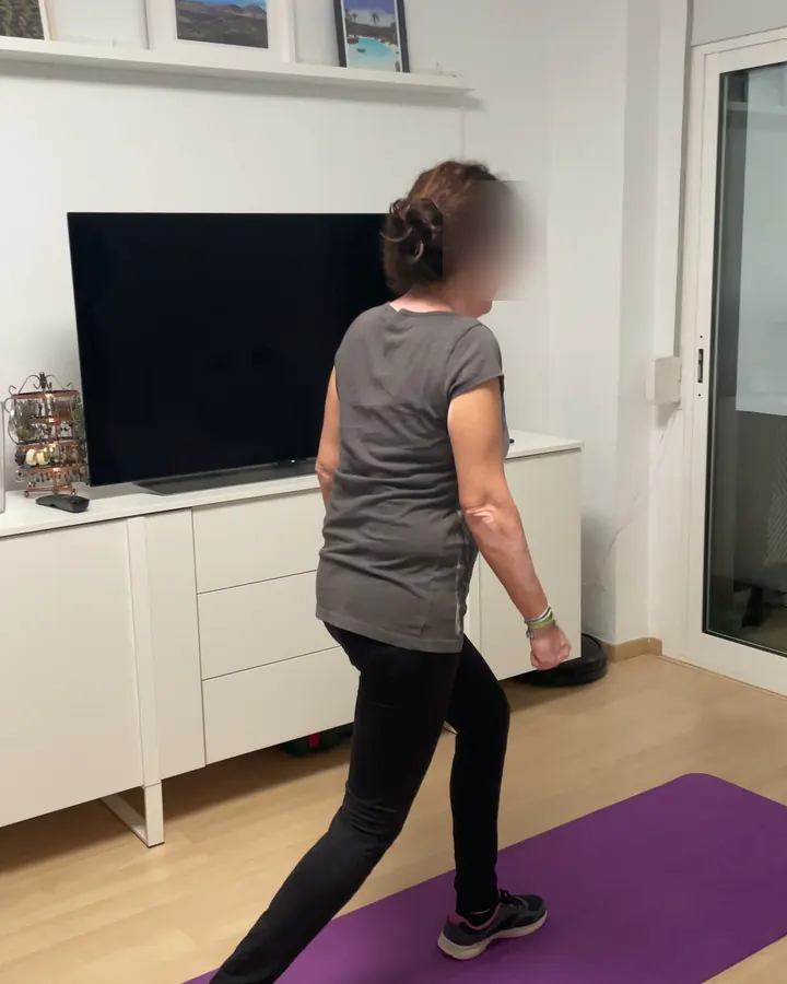 Clienta haciendo una zancada sobre una esterilla en el salón de su casa, en Málaga