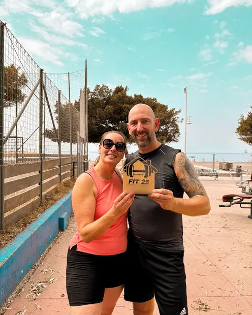 Pareja de clientes con la placa FIT 25 en una pista deportiva